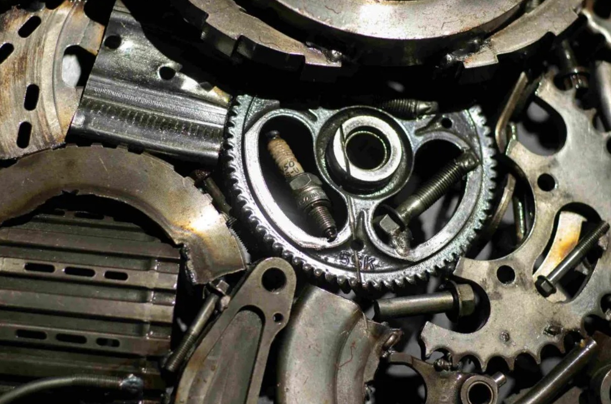 Close-up view of various interlocking metal gears, bolts, and spark plugs, showing the intricate components of a mechanical system