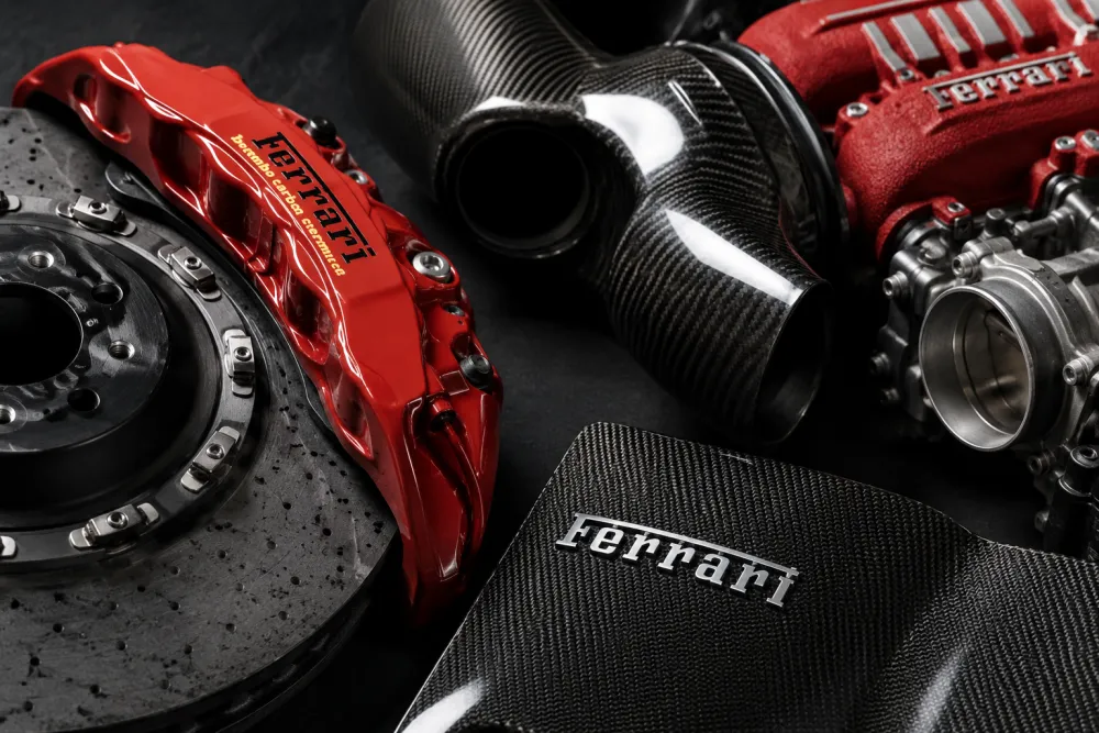 Close-up of Ferrari brake components, carbon fiber trim, and precision engine parts on a